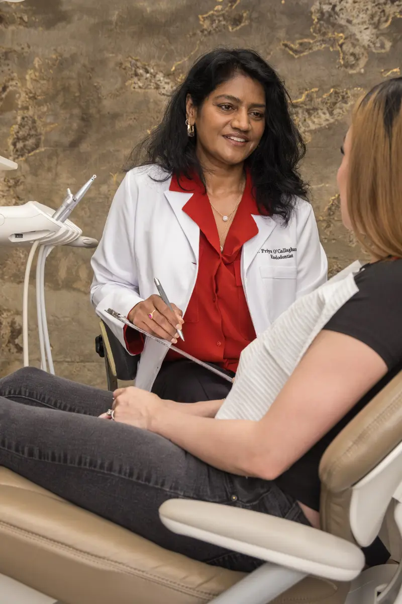 Dr. Priya O'Callaghan consulting with a patient in the treatment chair